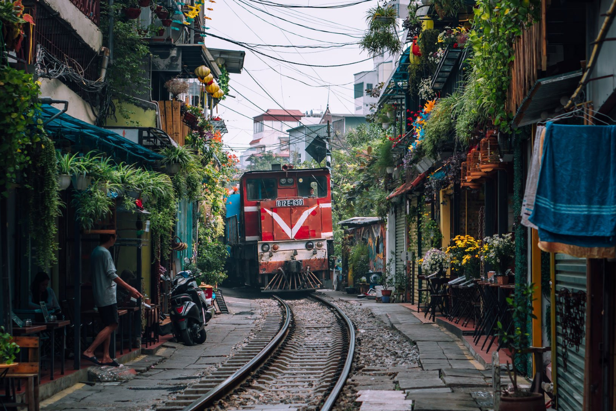 Train running closely past cafes and houses on Hanoi Train Street